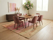7' x 9' Rectangular Pink Beige Wavy Geometric Abstract Modern Area Rug styled in a dining room with a wooden dining table, pink upholstered chairs, and modern chandelier.