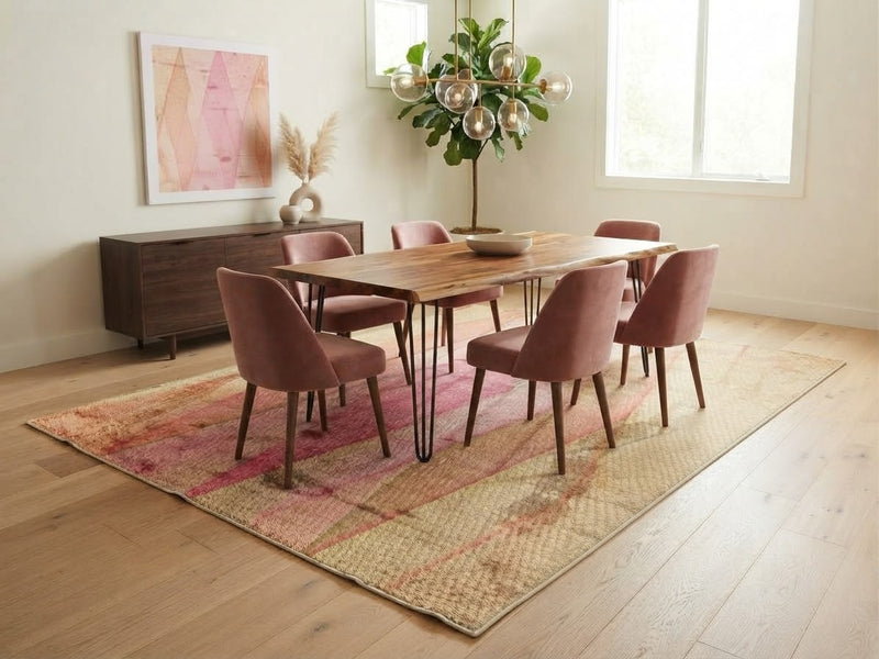7' x 9' Rectangular Pink Beige Wavy Geometric Abstract Modern Area Rug styled in a dining room with a wooden dining table, pink upholstered chairs, and modern chandelier.