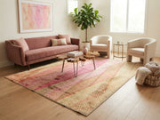 7' x 9' Rectangular Pink Beige Wavy Geometric Abstract Modern Area Rug styled in a living room with a dusty pink sofa, cream armchairs, and wooden coffee table.