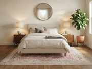 7' x 9' Rectangular Pink Ivory Distressed Floral Medallion Vintage Washable Area Rug placed in a bedroom with a cream upholstered bed, white bedding, and wooden nightstands.