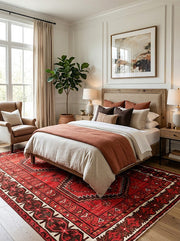 7' x 9' Rectangular Red Black Geometric Medallion Traditional Southwestern Area Rug placed in a bedroom with a beige upholstered bed, rust-colored bedding, and wooden nightstands.