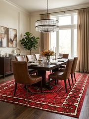 7' x 9' Rectangular Red Black Geometric Medallion Traditional Southwestern Area Rug styled in a dining room with a dark wooden dining table and brown leather chairs.