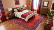 7' x 9' Rectangular Red & Purple Solid Border Contemporary Area Rug placed beneath a bed in a cozy bedroom.