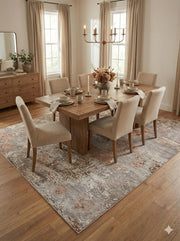 7' x 9' Silver Gray Rust Beige Ivory Abstract Modern Distressed Area Rug placed / styled in a dining room beneath a rustic wood table with upholstered beige chairs and soft natural lighting.