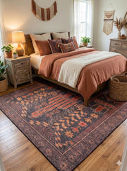 7' x 9' burgundy multi-color washable tribal medallion area rug placed in a cozy boho bedroom with a wooden bed frame, rust-toned bedding, and natural woven décor.