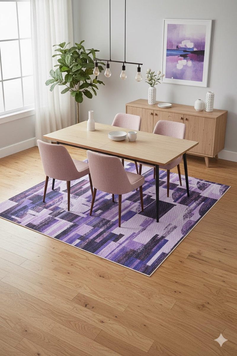 7' x 9' lavender, purple, and black geometric modern area rug placed beneath a light wood dining table with blush upholstered chairs.