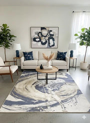 7' x 9' navy blue and beige abstract modern area rug styled in a contemporary living room with a neutral sofa, round coffee table, and navy accent pillows.