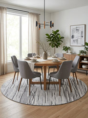 8' Round Gray Ivory Abstract Striped Modern Washable Area Rug styled in a dining room with a round wooden dining table and gray upholstered chairs.