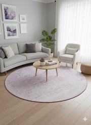 8' round light gray distressed modern rug styled under a coffee table in a contemporary living room with neutral seating and soft lavender artwork.
