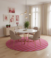 8' round pink and red striped modern rug placed under a round dining table with beige upholstered chairs in a soft, contemporary dining space.
