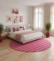 8' round pink and red striped modern rug styled beneath a bed with pink bedding and minimal décor for a warm, modern bedroom look.