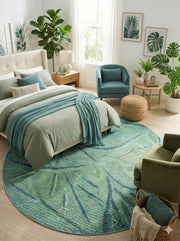 8' round sage green and muted blue abstract botanical area rug styled in a bright bedroom with soft green bedding, natural wood furniture, and leafy plant décor.