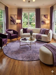 8' round taupe and light gray distressed abstract area rug styled in a modern living room with a curved cream sofa, purple accent chairs, and soft lavender décor.