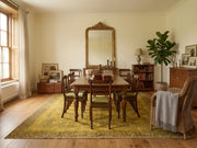 8' x 10' Mustard Gold Brown Distressed Floral Medallion Traditional Area Rug styled in a dining room with a wooden table, green upholstered chairs, and vintage decor.