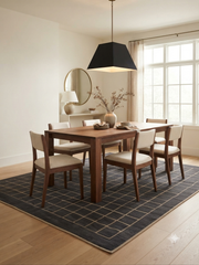 8' x 10' Rectangular Charcoal Gray Beige Grid Geometric Modern Washable Area Rug styled in a minimalist dining room with a wooden dining table, cream upholstered chairs, black pendant light, and large windows.