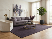 8' x 10' Rectangular Charcoal Gray Dark Gray Solid Textured Modern Minimalist Washable Area Rug styled in a living room with a gray sofa and round coffee table.