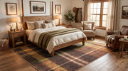 8' x 10' Rectangular Dark Brown Rust Gold Plaid Checkered Modern Area Rug placed in a rustic farmhouse bedroom with a wooden bed frame, cream bedding, wooden nightstands, and brown leather armchair.