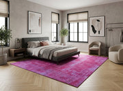 8' x 10' Rectangular Fuchsia Pink Lavender Distressed Floral Medallion Vintage Washable Area Rug placed in a bedroom with a gray upholstered bed and beige accent chairs.