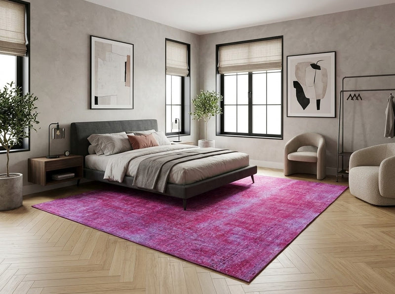 8' x 10' Rectangular Fuchsia Pink Lavender Distressed Floral Medallion Vintage Washable Area Rug placed in a bedroom with a gray upholstered bed and beige accent chairs.