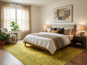 8' x 10' Rectangular Mustard Gold Gray Distressed Floral Medallion Traditional Washable Area Rug placed in a bedroom with a beige upholstered bed, wooden nightstands, and mustard gold accent pillows.