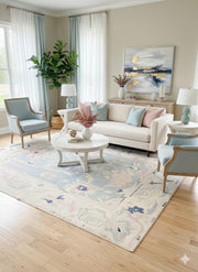 8' x 10' ivory cream and mist blue washable abstract vintage area rug placed in an elegant living room with a neutral sofa, pastel blue accent chairs, and soft blush and blue decorative pillows.