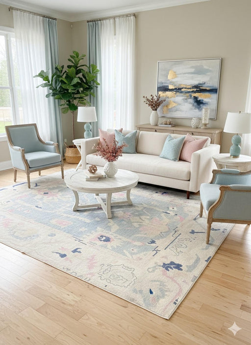8' x 10' ivory cream and mist blue washable abstract vintage area rug placed in an elegant living room with a neutral sofa, pastel blue accent chairs, and soft blush and blue decorative pillows.