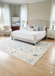 8' x 10' ivory cream and mist blue washable abstract vintage area rug styled in a bright bedroom with a neutral upholstered bed, soft pastel accent pillows, and light wood flooring.
