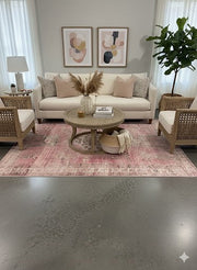 8' x 10' pink and ivory distressed medallion vintage area rug styled in a soft neutral living room with cream sofa, woven accent chairs, and light wood coffee table.