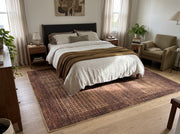 8' x 12' Rectangular Burgundy Brown & Gold Abstract Grid Modern Washable Area Rug placed beneath a bed with white bedding and a dark upholstered headboard.