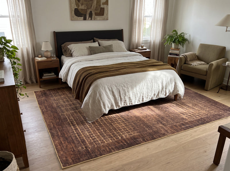 8' x 12' Rectangular Burgundy Brown & Gold Abstract Grid Modern Washable Area Rug placed beneath a bed with white bedding and a dark upholstered headboard.