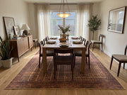8' x 12' Rectangular Burgundy Brown & Gold Abstract Grid Modern Washable Area Rug styled in a dining room beneath a wooden dining table and dark wooden chairs.
