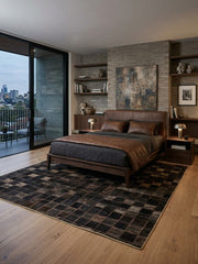 8' x 12' Rectangular Dark Brown Black Checkered Geometric Modern Area Rug placed in a modern bedroom with a brown upholstered bed and dark bedding.