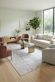 8' x 12' Rectangular Ivory Light Blue Distressed Tribal Vintage Washable Area Rug styled in a modern living room with a white sofa and pink accent chairs.