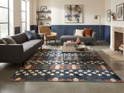 8' x 12' Rectangular Navy Blue Red Stars and Stripes Patriotic Americana Area Rug styled in a modern living room with a charcoal gray sofa, mustard accent chair, wooden coffee table, and navy blue wall paneling.
