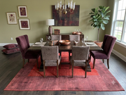 8' x 12' Rectangular Rust Red Burgundy Solid Border Modern Contemporary Area Rug styled in a sophisticated dining room with a dark wooden dining table, burgundy upholstered chairs, gray accent chairs, and a classic chandelier.