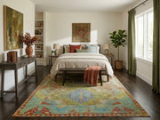 8' x 12' Rectangular Sage Green Blue Distressed Geometric Medallion Southwestern Washable Area Rug placed in a bright bedroom with a beige upholstered bed, neutral bedding, and green curtains.