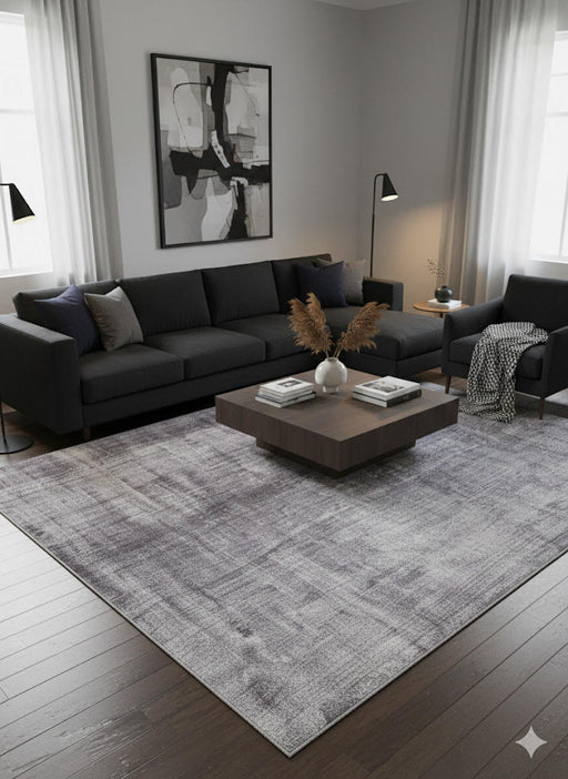 8' x 12' gray and ivory distressed abstract area rug styled in a modern living room with a black sectional sofa, minimalist décor, and a dark wood coffee table.