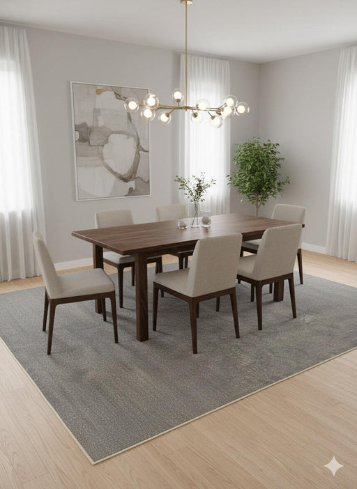 8' x 12' gray and soft beige distressed solid washable area rug styled beneath a modern wooden dining table with upholstered chairs in a bright minimalist dining room.