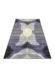 8' x 12' modern washable area rug featuring an abstract symmetrical design in shades of purple, gray, charcoal, and cream with a non-slip backing.