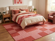 8' x 12' red and pink modern geometric checkered washable area rug styled beneath a bed in a warm contemporary bedroom with soft neutral bedding and blush accents.