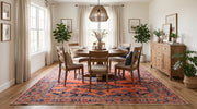 8' x 8' Square Rust Orange & Navy Blue Tribal Geometric Traditional Area Rug styled in a dining room beneath a round wooden dining table and cushioned chairs.