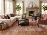 8' x 8' square rose pink and beige distressed vintage washable area rug styled in a bright living room with a neutral sectional sofa, accent chairs, and a wood coffee table.