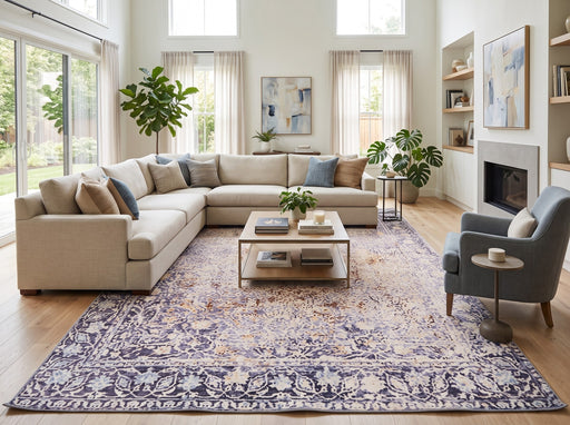 8' x 12' Rectangular Ivory Lavender Gold Distressed Floral Medallion Vintage Traditional Area Rug styled in a bright modern living room with a cream sectional sofa, blue-gray accent chair, wooden coffee table, and large windows.
