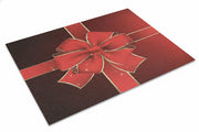 Rectangular holiday rug featuring a large poinsettia gift-bow design in rich red with gold accents on a dark burgundy background.