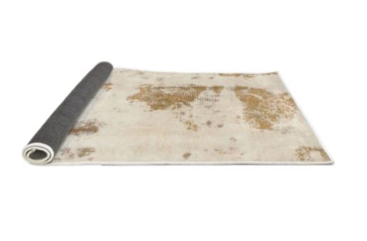 Side view of the 2' x 3' ivory and gold distressed abstract accent rug partially rolled to display the backing and construction.