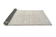 Side view of the rug partially rolled to display the backing and construction.